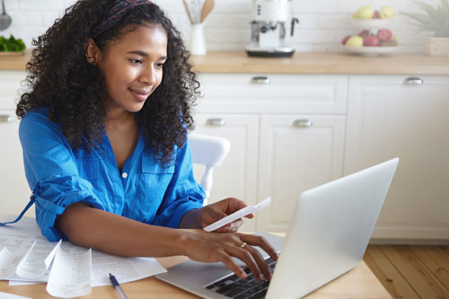 Member reviewing statements on a laptop at her kitchen table